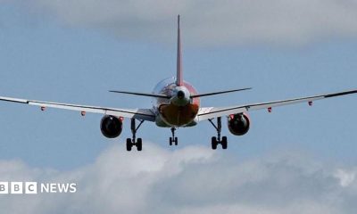 A red and white plane, with blue sky and clouds in the background