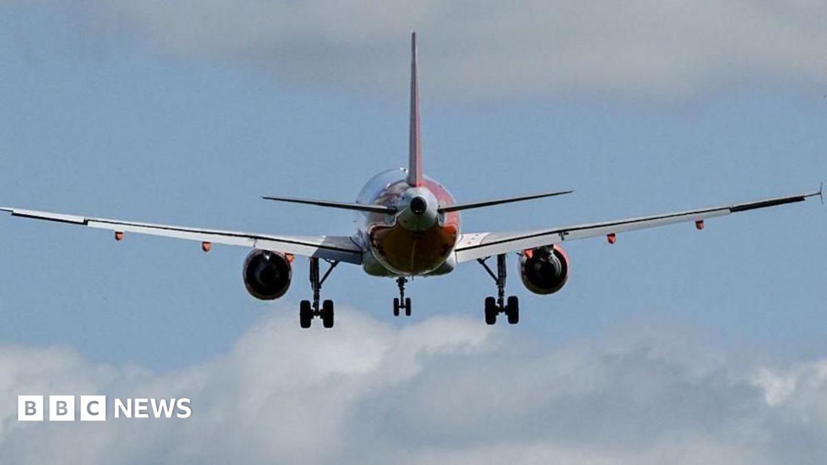 A red and white plane, with blue sky and clouds in the background