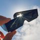 A pair of eclipse glasses held up in front of the sun