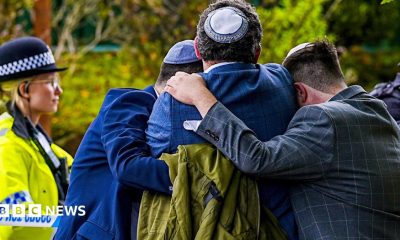 Worshippers console each other after the attack o0n their synagogue while a police officer looks on.