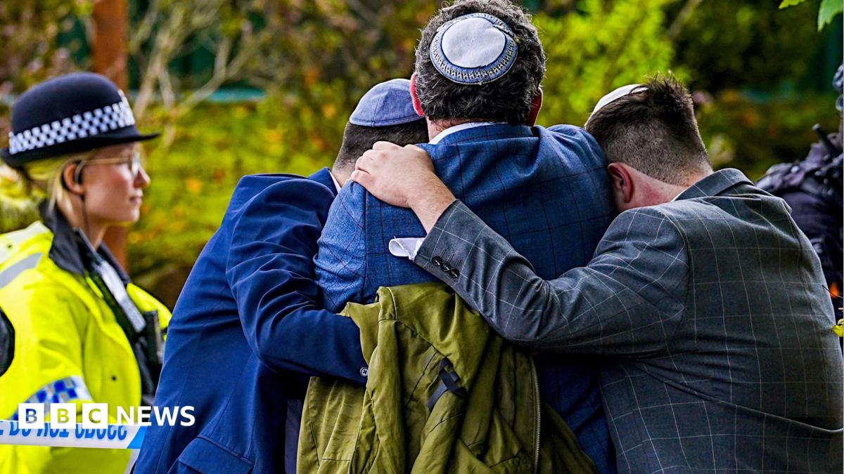 Worshippers console each other after the attack o0n their synagogue while a police officer looks on.
