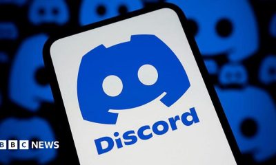 The blue Discord logo on a phone against a white background. In the background are more Discord logos on a black background.