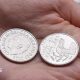 New 10p coin in the palm of someone's hand with one coin on the side showing an image of King Charles and dated 2026, with another coin on the reverse side showing a capercaillie.