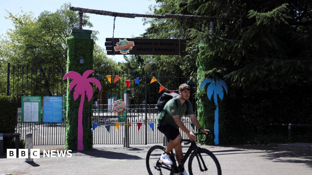 The closed gates of the theme park with a staff member in front