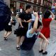 People holding umbrellas along a street in Shanghai. One boy is seen trying to hold on to an inverted umbrella as winds intensify