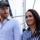 Harry and Meghan seen walking together in Sydney harbour in April. He is wearing a blue shirt and a cap, she is wearing a striped blue shirt.