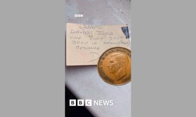 An old penny on top of a piece of card - on it is written: David Judd - one pint of best beer if penny returned
