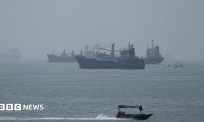 Large ships in the Strait of Hormuz are visible near the beach of Bandar Abbas.