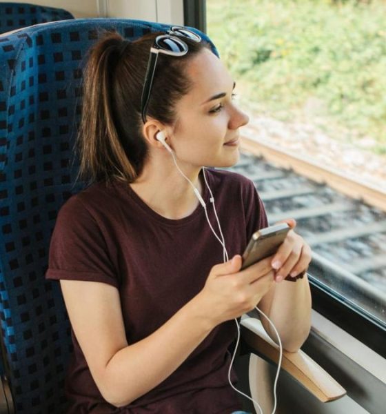 A teenage girl sitting on a train listening to headphones