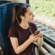 A teenage girl sitting on a train listening to headphones