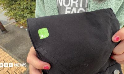 A close-up of a black pair of trousers. There is a green square sticker on them.