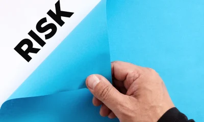 To uncover hidden business risks concept. Male hand opens the blue paper and reveals the word risk.
