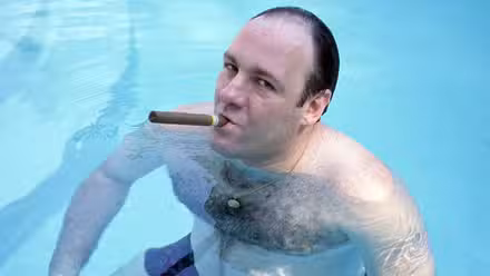 James Gandolfini smoking a cigar and looking into the camera from a pool for The Sopranos