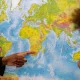 Black male's hand points to Africa on the world map as a black boy looks on from the side with his hand covering his mouth
