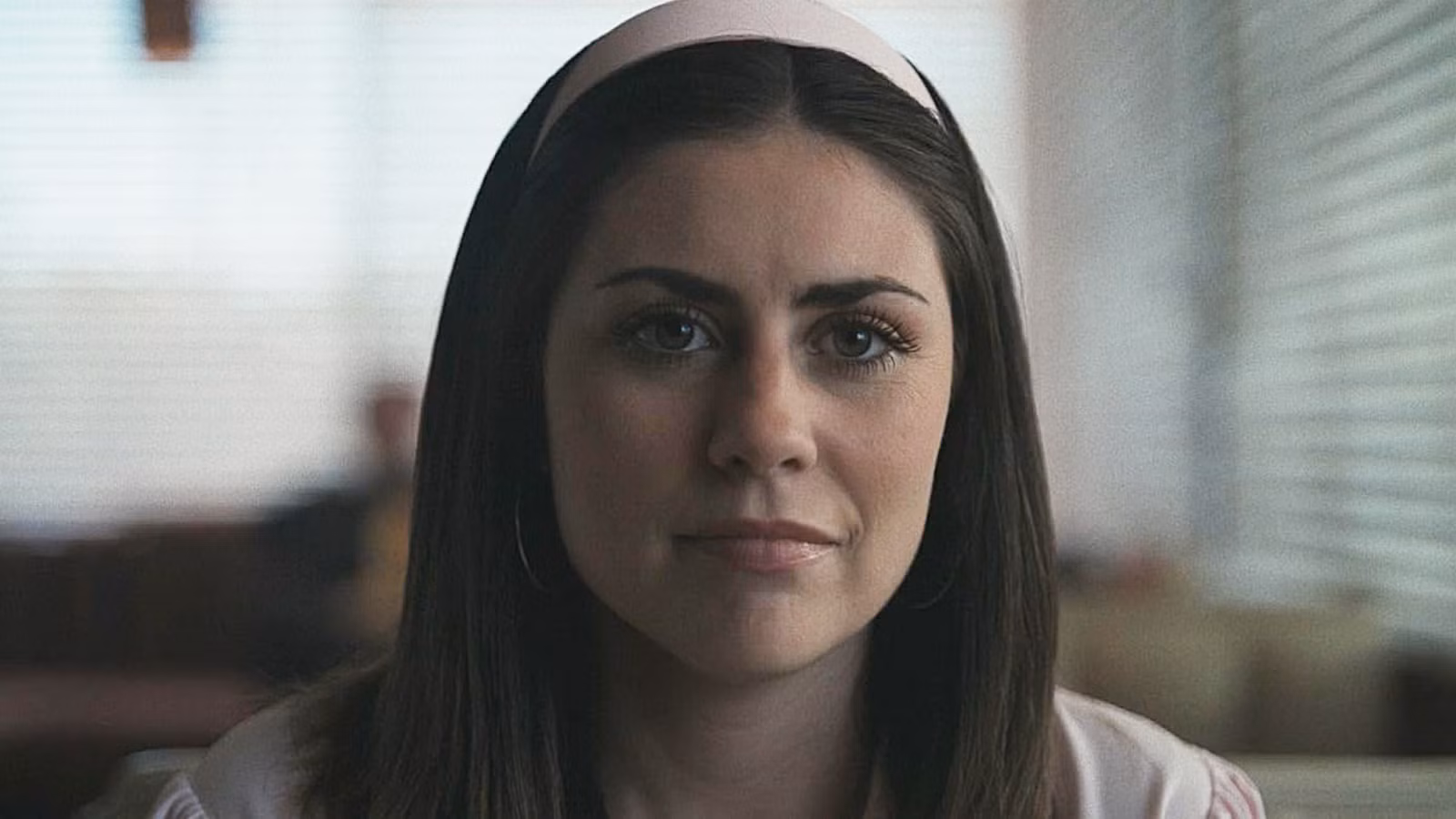 Chloe Breen wearing a white headband sat in a diner booth in 'Obsession'