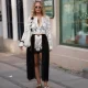 COPENHAGEN, DENMARK - AUGUST 3: A guest is seen wearing a white floral lace cropped cardigan with black floral appliqué detailing layered over a black bralette; ivory satin lace trim shorts; a sheer black lace wrap skirt; brown suede lace up sneakers with contrast stitching from Acne Studios; a white woven leather shoulder bag with black floral embellishments; white cat eye sunglasses; gold hoop earrings; and layered pendant necklaces during Day One of Copenhagen Fashion Week Spring/Summer 2027, outside the Modström by Prudence Davis event, on August 3, 2026 in Copenhagen, Denmark. (Photo by Moritz Scholz/Getty Images)