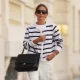 PARIS, FRANCE - MAY 26: Diane Batoukina wears brown hair with a center part pulled into a low bun, black oversized square sunglasses with dark lenses by Kaleos, a white crew neck t-shirt, a white knit button-front sweater with black horizontal stripes by Anna V Berg, white straight-leg jeans pants by Comptoir des Cotonniers, a silver-tone watch, a black quilted leather shoulder bag with a silver-tone chain strap and silver-tone logo hardware by Chanel, white sneakers shoes by Prada, during a street style fashion photo session, on May 26, 2026 in Paris, France. (Photo by Edward Berthelot/Getty Images)