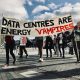 Protestors against AI data centres holding a banner that reads, "Data centres are energy vampires"