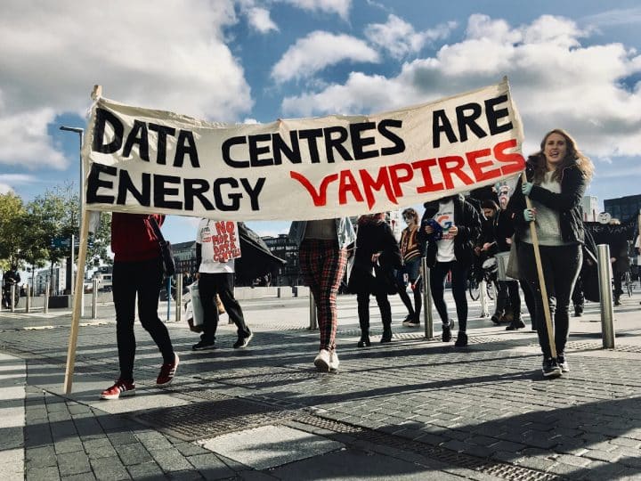 Protestors against AI data centres holding a banner that reads, "Data centres are energy vampires"