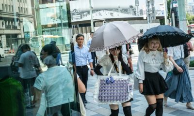 Women walk with umbrellas to shield themselves from the sun in Tokyo