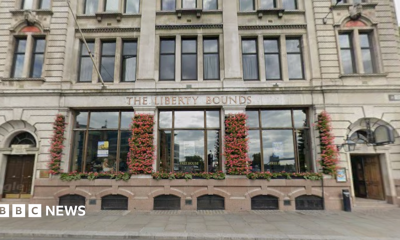 The exterior of a pub with large windows and flowers growing on the walls