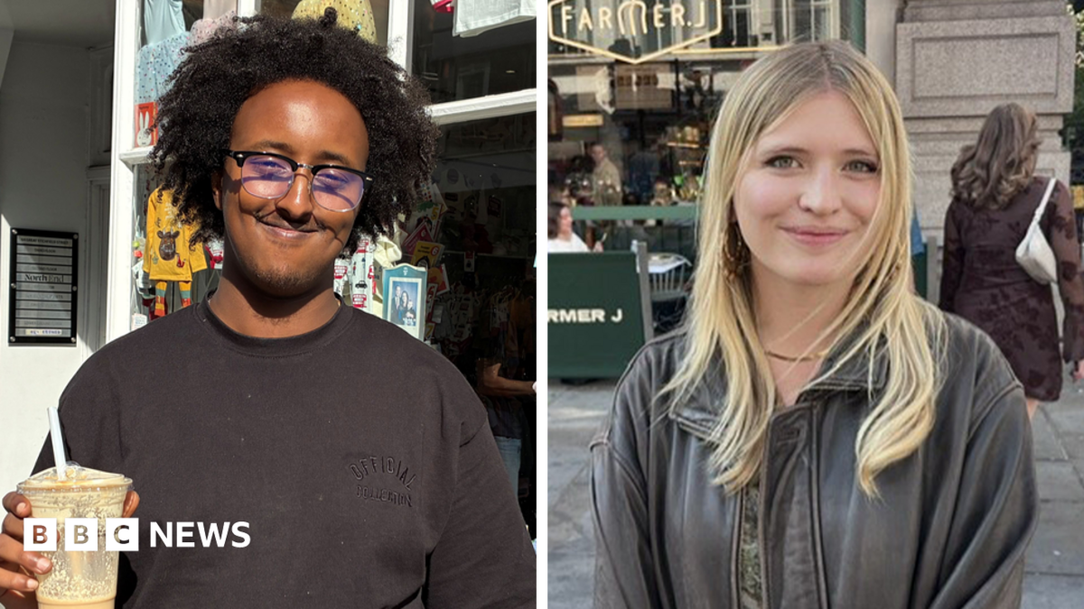 Hanad, wearing a glasses and a black T-shirt and holding an iced coffee, smiles as he stands outside a shop in London.