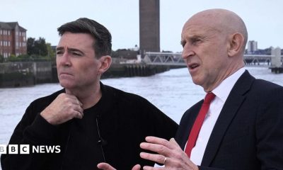 John Healey makes a point with his hands to a thoughtful looking Andy Burnham, who is gazing out across the Mersey river on a ferry in Liverpool