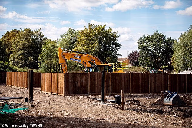 Pictured: a JCB digger parked inside wooden fencing used to divide the site into plots of land