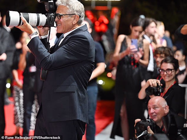 George Clooney cheekily plays photographer on the Venice Film Festival red carpet as his film Furies receives rave reviews from critics