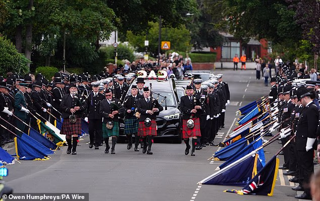 Bagpipers lead the funeral cortege through the streets lined with police colleagues