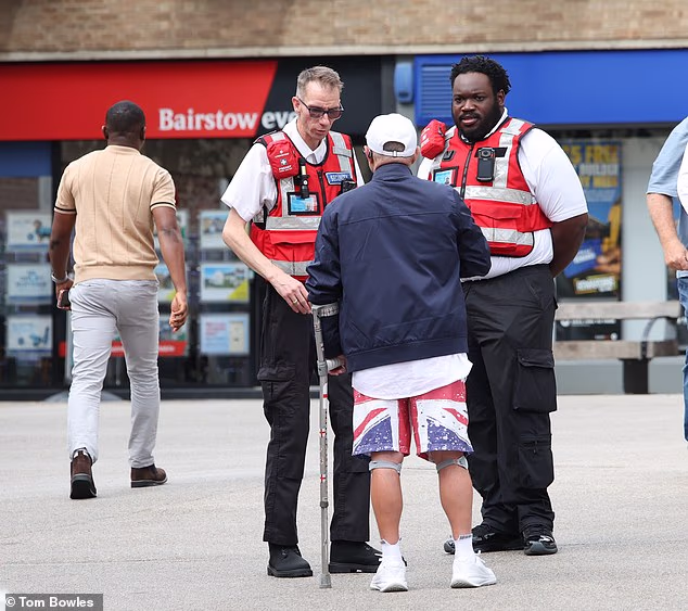 Two private security guards speak to a local in Braintree, Essex, after the Reform-led county council launched patrols aimed at monitoring migrants