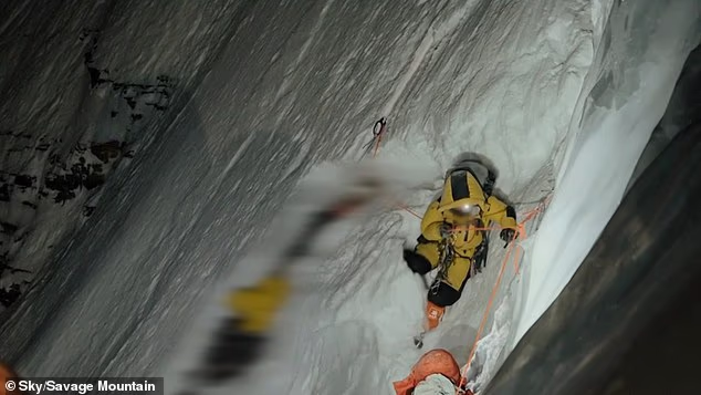 A climber is seen attempting to save a dying porter before dangerously slipping