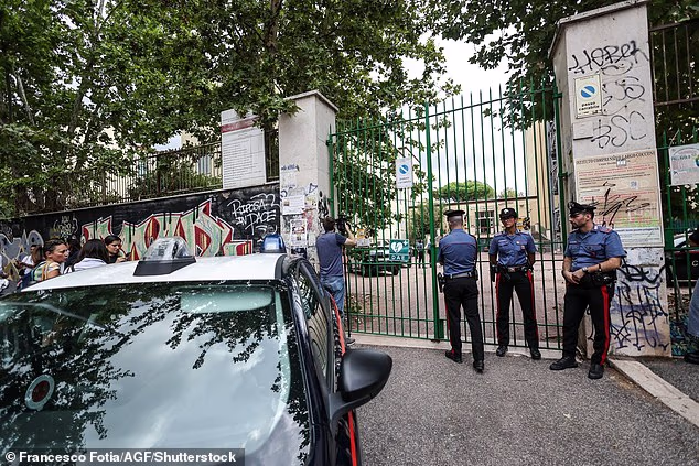 A 13-year-old student pepper-sprayed his teacher before stabbing her and attempting to livestream the attack at a school in Rome. Pictured: Police standing outside the school gates following the incident