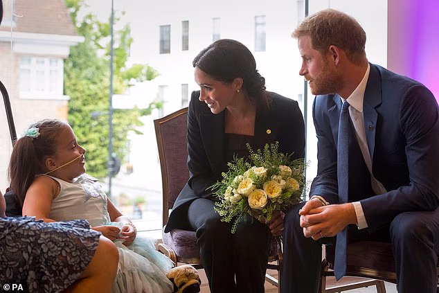 The Duke and Duchess of Sussex meet a child during the 2018 WellChild Awards in London