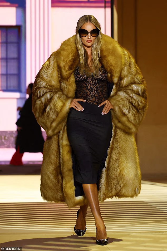 Rosie Huntington-Whiteley commanded attention in a sheer lace top and oversized fur coat on the catwalk at the star-studded Gucci show during Milan Fashion Week