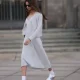 Jill Asemota seen wearing black vintage sunglasses, Dorothee Schumacher grey wool knit long dress, matching Dorothee Schumacher grey wool knit cardigan jacket, white cotton socks, Adidas white leather Samba sneakers, on November 04, 2023 in Berlin, Germany.
