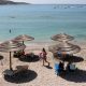 The beach with the sea in the background. There are sun beds and straw shades