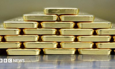 Gold bars are neatly stacked on top of each other to form a pyramid shape.