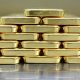 Gold bars are neatly stacked on top of each other to form a pyramid shape.