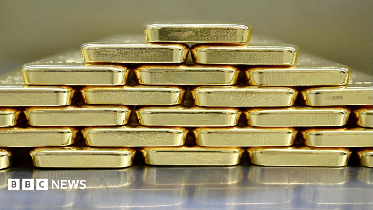 Gold bars are neatly stacked on top of each other to form a pyramid shape.