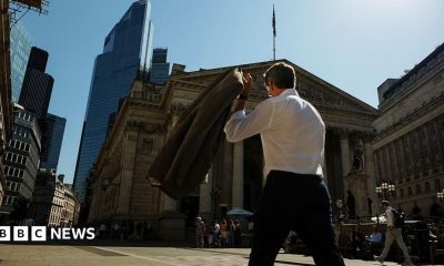 A commuter carries his jacket on a sunny day in the City of London
