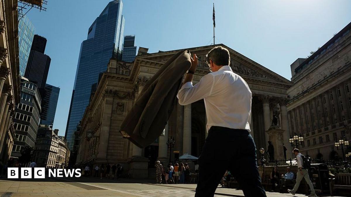 A commuter carries his jacket on a sunny day in the City of London