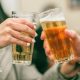 A pair of beer-filled glasses being knocked together in a bar setting.