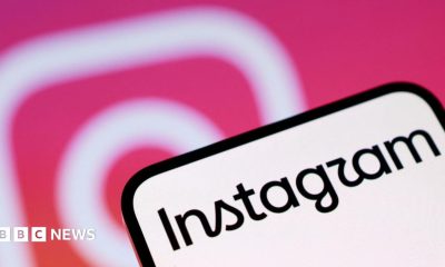 A phone screen with Instagram written on it. In the background is the pink and white Instagram camera logo