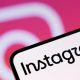 A phone screen with Instagram written on it. In the background is the pink and white Instagram camera logo