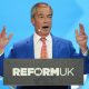 Nigel Farage holds up his hands as he gives his conference speech from behind a podium with Reform UK's logo.