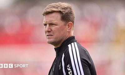 Eddie Howe, wearing a black-and-white tracksuit stop, looks on before a Newcastle match