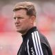 Eddie Howe, wearing a black-and-white tracksuit stop, looks on before a Newcastle match