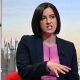 Bridget wears a navy blazer over a purple top sitting and talking in front of the illustrated Sunday with Laura Kuenssberg set.