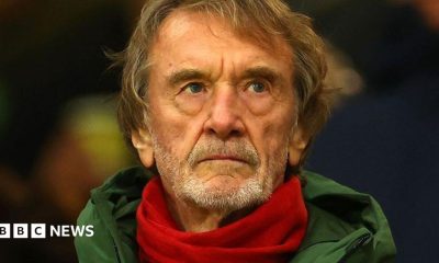 Sir Jim Ratcliffe in a green coat and red scarf